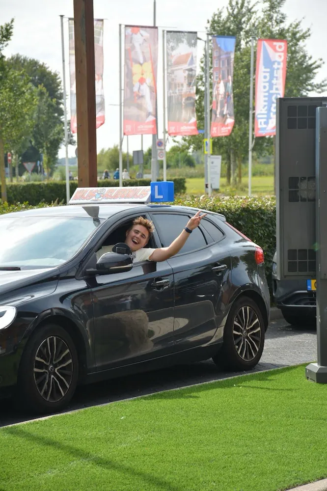 kans op succes Rijschool Noord-Holland - Student met duimen omhoog naast lesauto